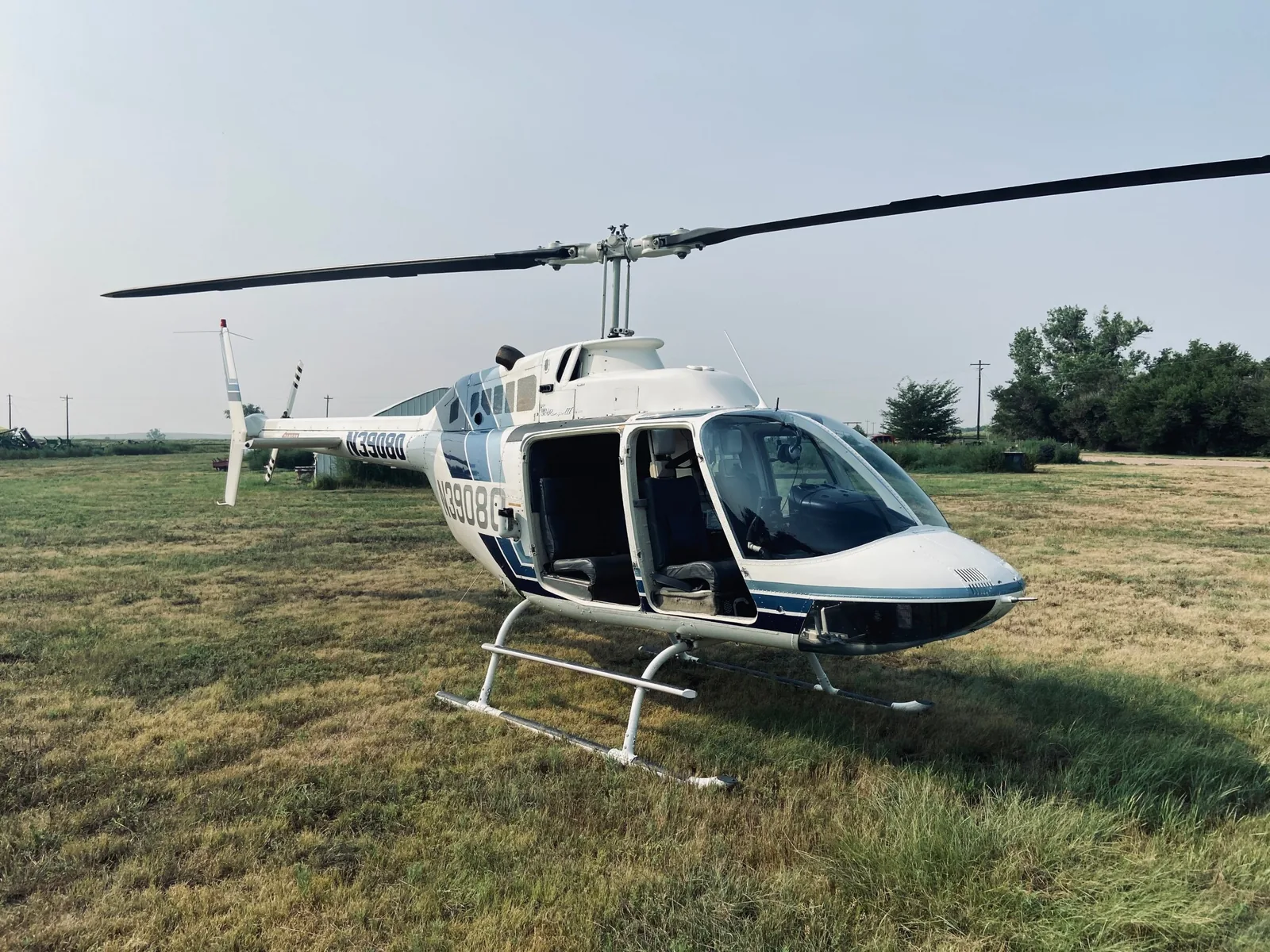 A Bell helicopter parked on grass with its rotor at rest