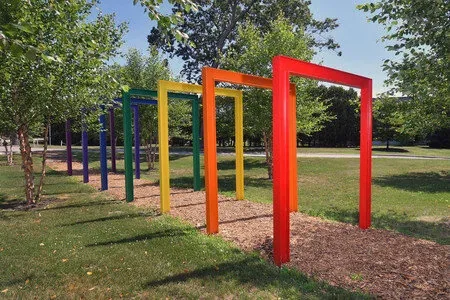 Beyond the Rain, a row of rainbow-colored open frames in a grove on the Wheaton campus